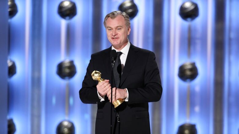 man holding award wearing black suit