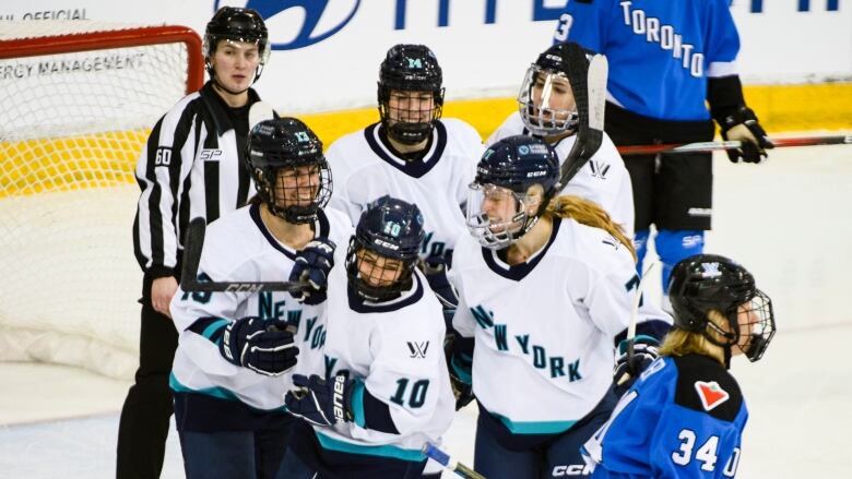 A bunch of New York hockey player4s smile and celebrate after a goal.