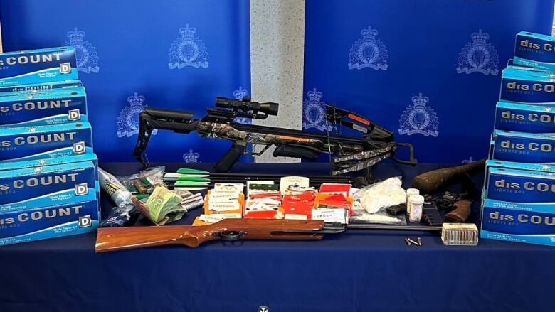 a table with an rcmp logo is filled with drugs and weapons. 