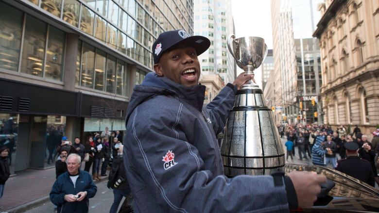 A football player celebrates with a trophy.