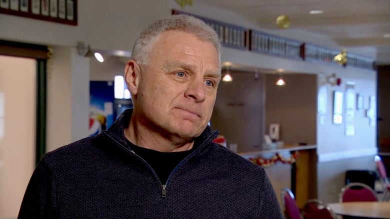 A man with grey hair speaks to a reporter off camera.