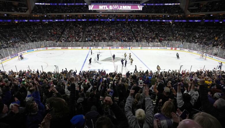 Fans cheer before puck drop at a hockey game.