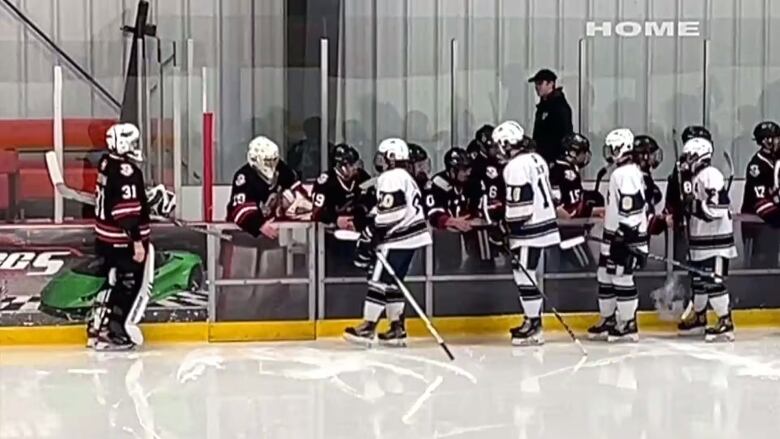 A hockey team skates by the opposing team's bench in a handshake line.