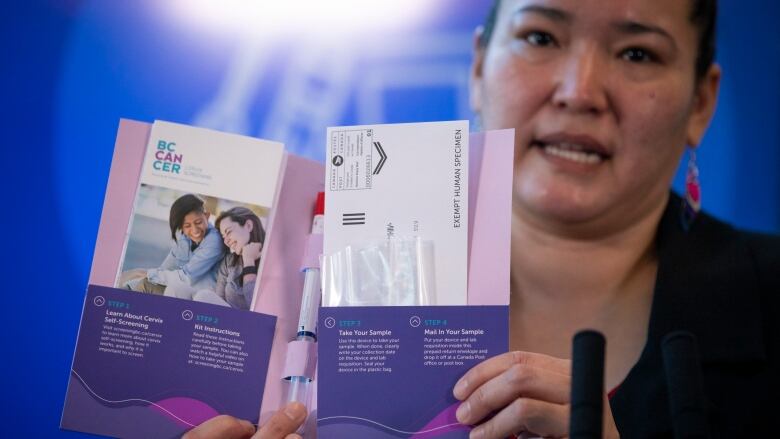 A First Nations women holds at-home cervical cancer screening materials at a provincial press conference.