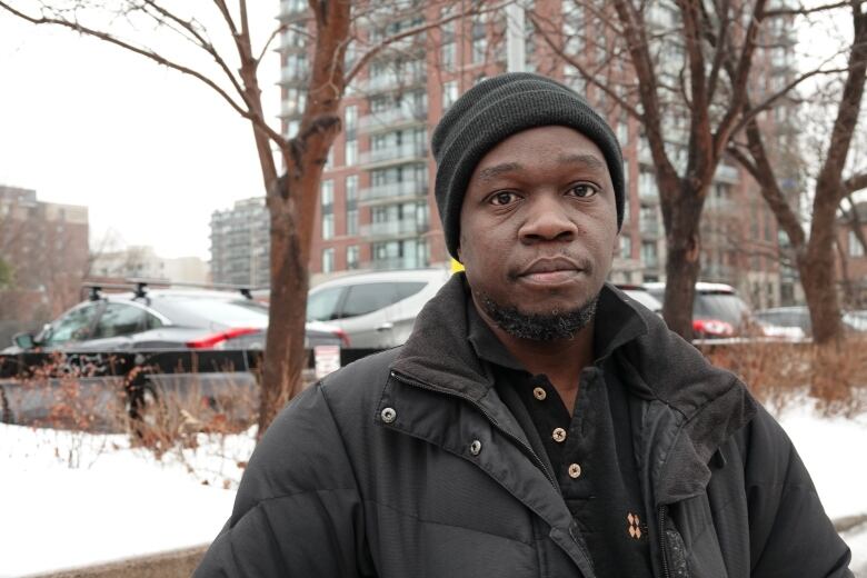 A parent poses for a photo outside a school in winter.