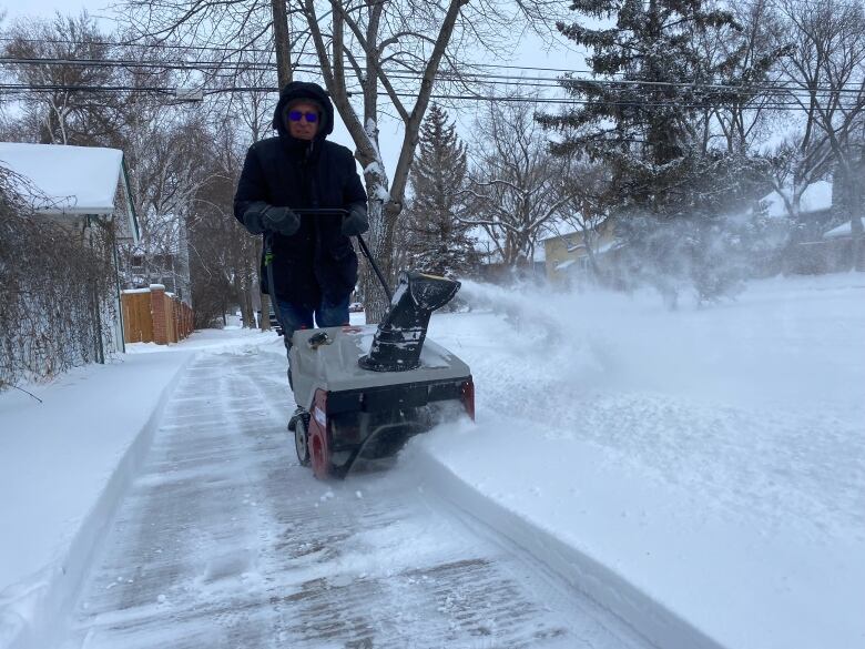 A man clearing the sidewalk of snow in Saskatoon after 15 cm fell over night.