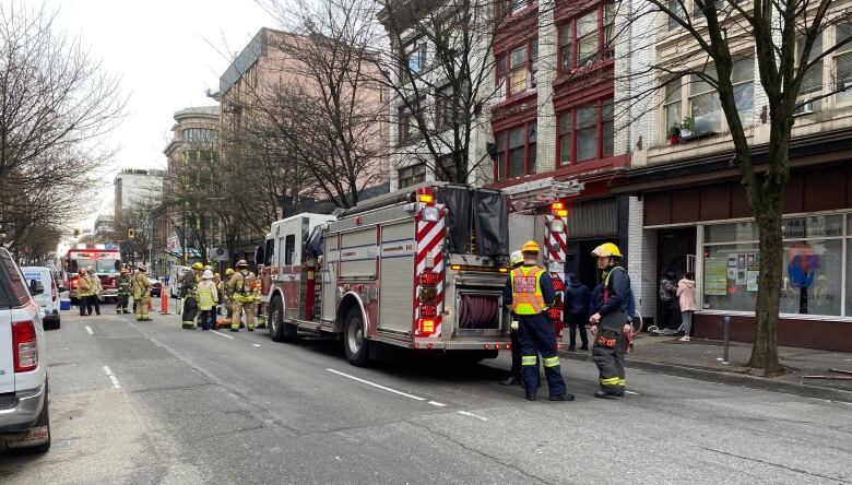 Fire crews and a fire truck are stationed outside a row of low-rise residential buildings.