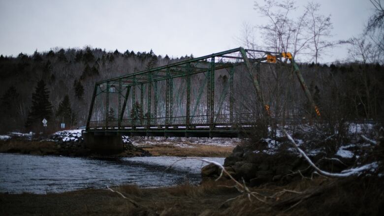 a green steel bridge over a river in winter 