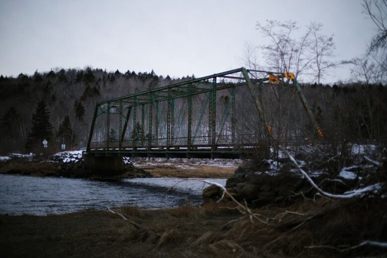 a green steel bridge over a river in winter 