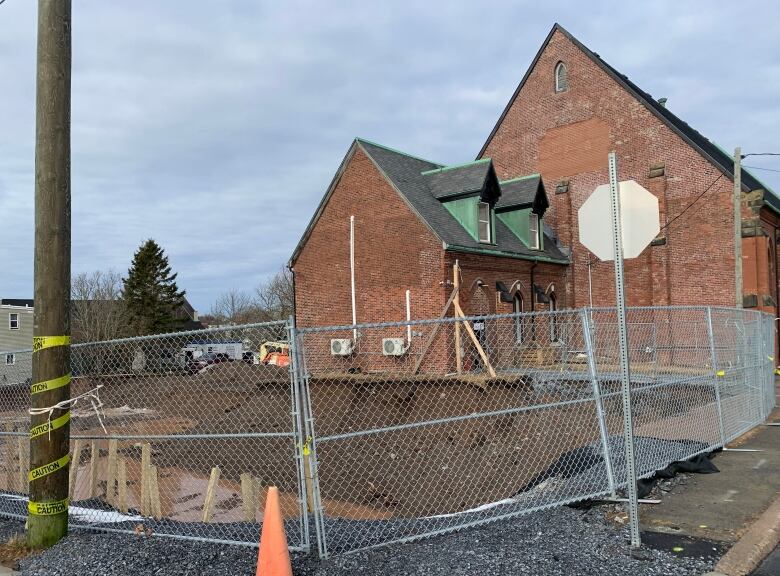 Lot behind building with large hole in ground for building construction.