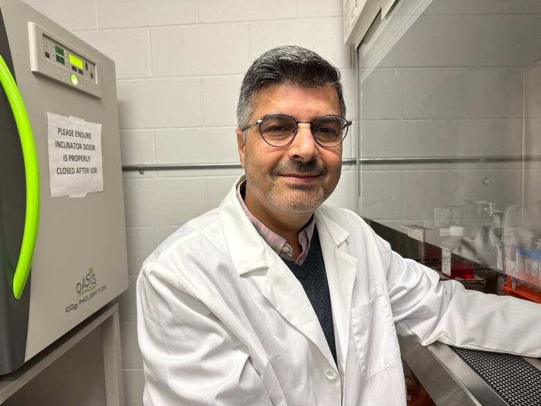 A man sits in a lab coat in a lab.