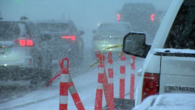 A line of traffic is obscured by heavy snowfall.