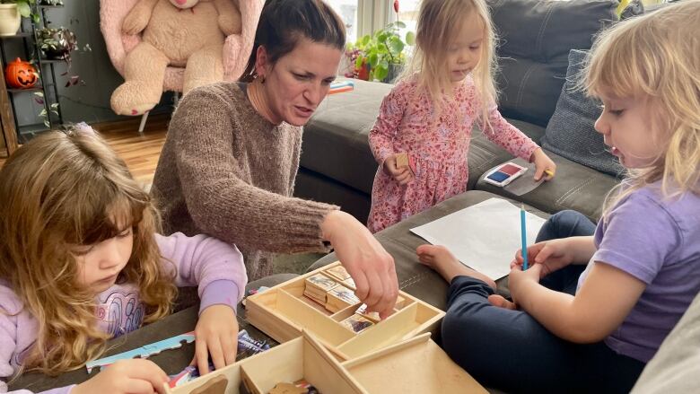 A woman with brown hair in a pony tail plays table-top games with small children