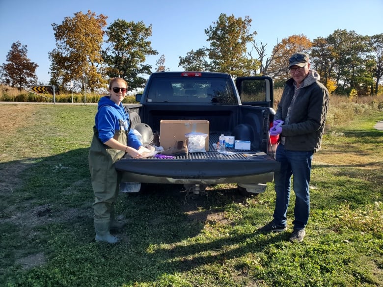 Two people stand by the bed of a pickup truck containing scientific equipment. 