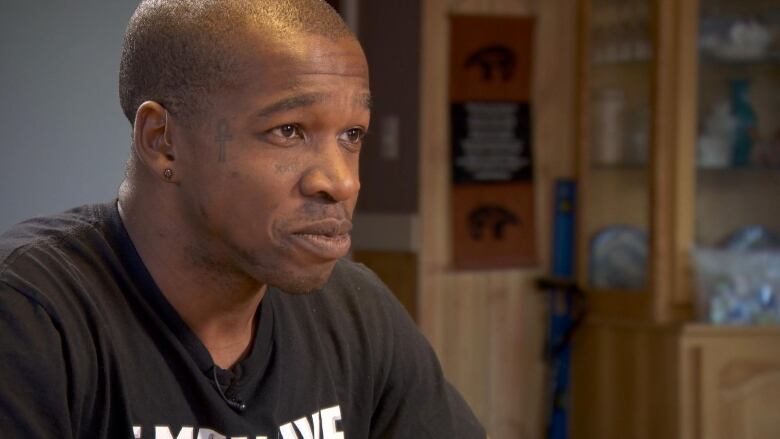 Head and shoulders shot of a Black man with face tattoos. 