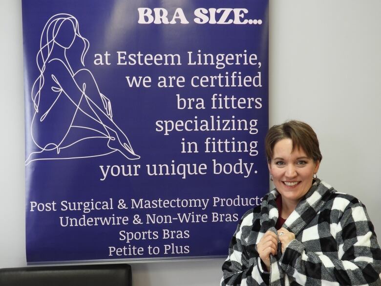 A woman stands in front of a sign.