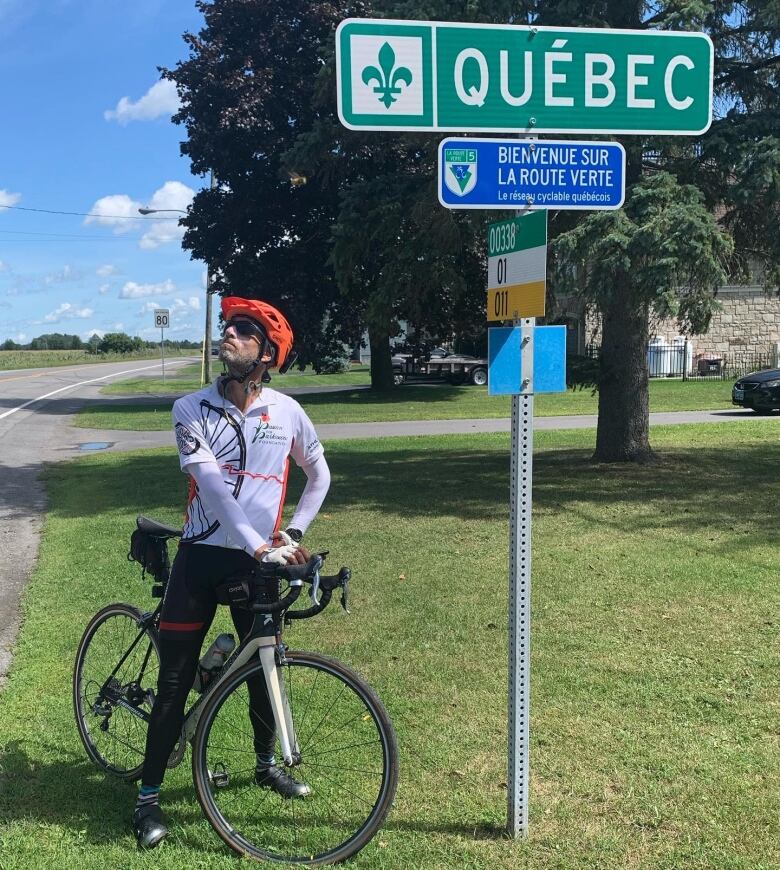 Man on bicycle beside sign that says 