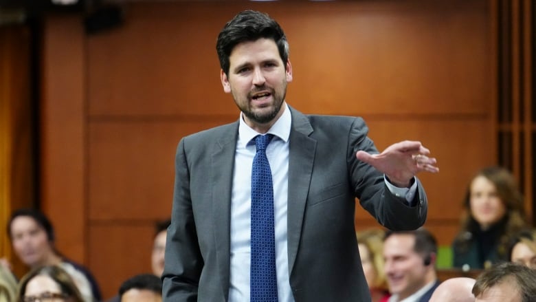 A man in a gray suit speaks in the House of Commons.