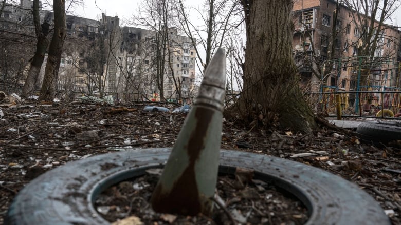 A part of a rocket sticks up from the ground in front of a residential building bombed by Russian forces in the frontline city of Vuhledar, Ukraine on Feb. 25, 2023.