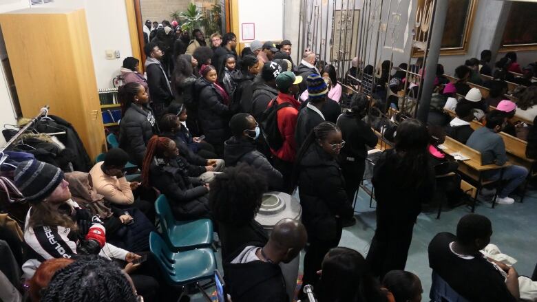 Several people stand at the back of a chapel during a memorial service.