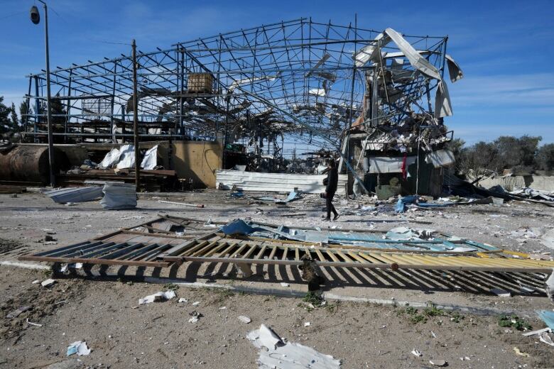 A Palestinian is seen walking past factory facilities that were destroyed by Israeli bombardment in Deir al Balah, Gaza.