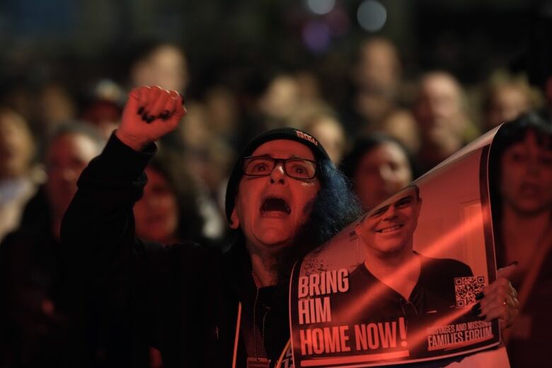 A woman holds a photo of a hostage during a rally in Tel Aviv.