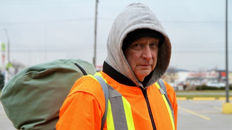 Man with sleeping bag on back in parking lot