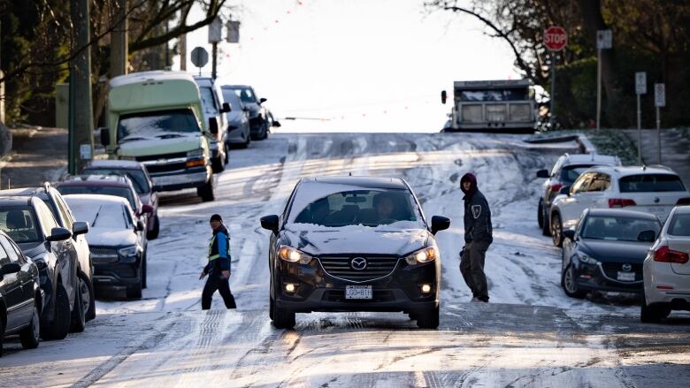 A car is seen driving down an icy hill. 