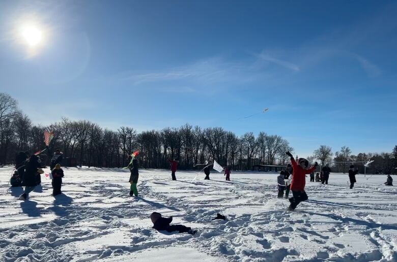 Kids fly kits in a snowy field.