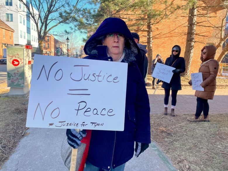 Woman holds sign that reads No Justice = No Peace.