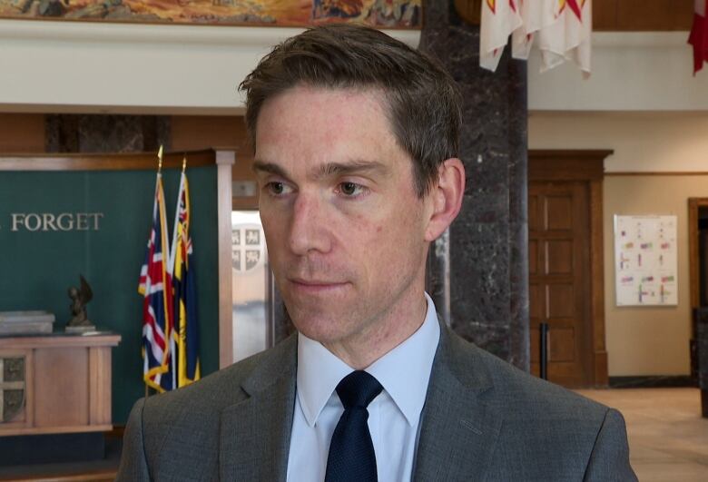 A man in a grey suit stands in the lobby of a government building. 