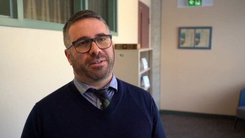 A man wearing glasses and a sweater vest. 