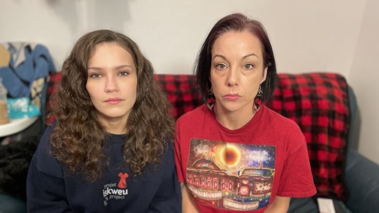 Two women sit next to each other on a couch.