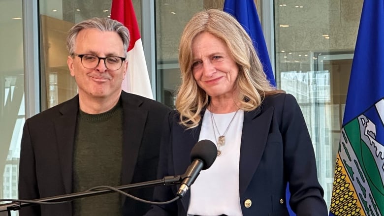 A woman and a man stand behind a podium.