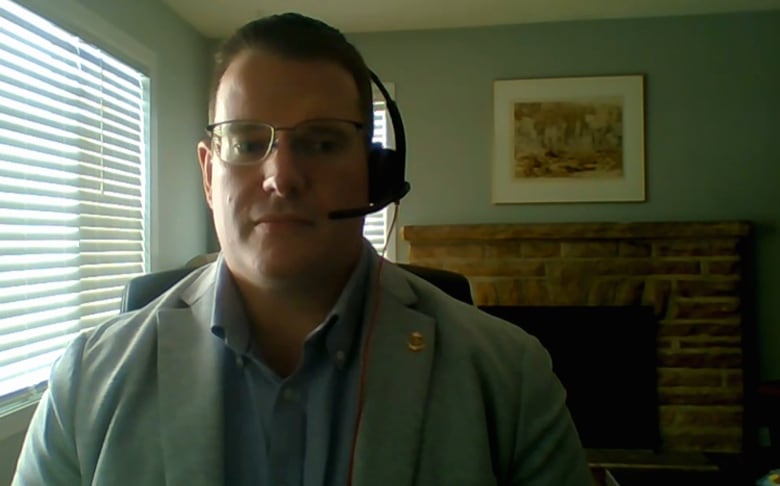 A man wearing glasses and a headset looks at the computer in a Zoom call.