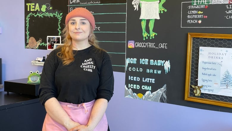 Emily Flint stands in front of blackboard coffee shop menu