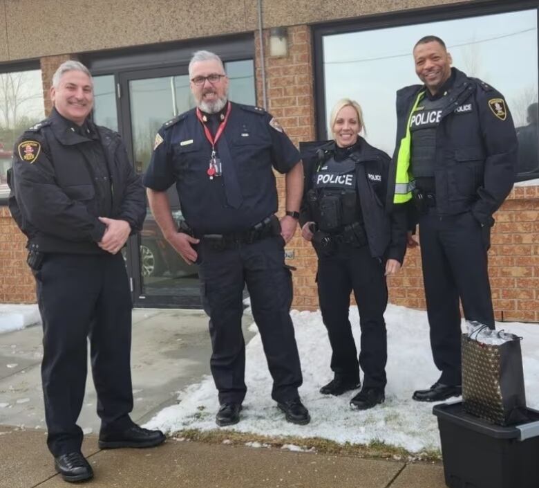 Four police officers pose for the camera outdoors.