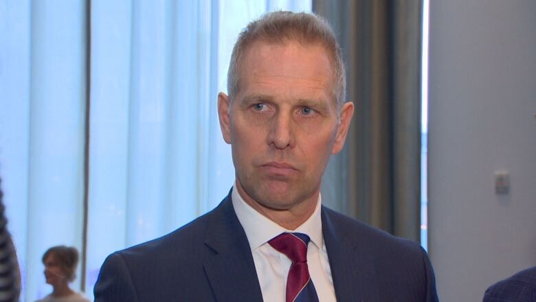 A man wearing a suit with a red tie past the camera.