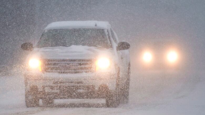 A white truck drives through snow.