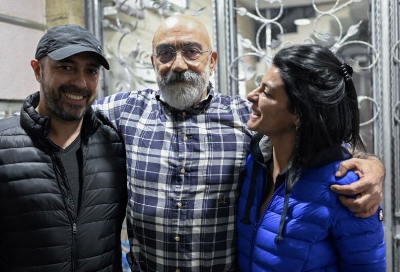 Turkish journalist and writer Ahmet Altan (C), with his children Kerem (L) and Senem (R), poses for AFP at his home minutes after he arrived following his release from jail, at Kadikoy neighbourhood in Istanbul,