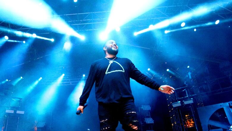 A smiling man stands in front of bright lights on a stage. 