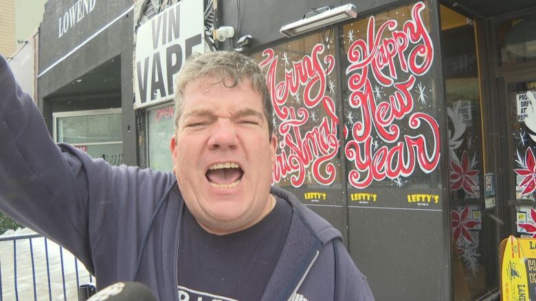 A man on a downtown street cheers for a sports team.