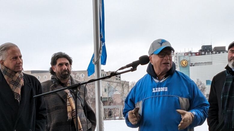 Men at a flagpole, one of them wearing clothing branded with a football team.