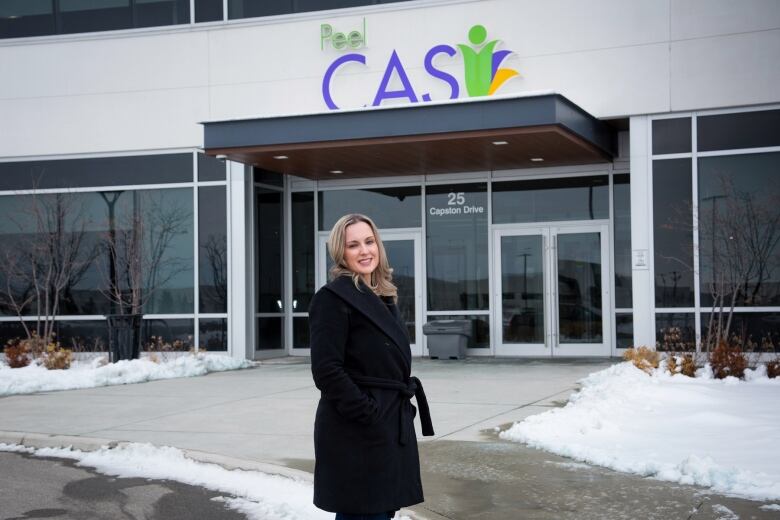 A woman stands in front of Peel Children's Aid. 