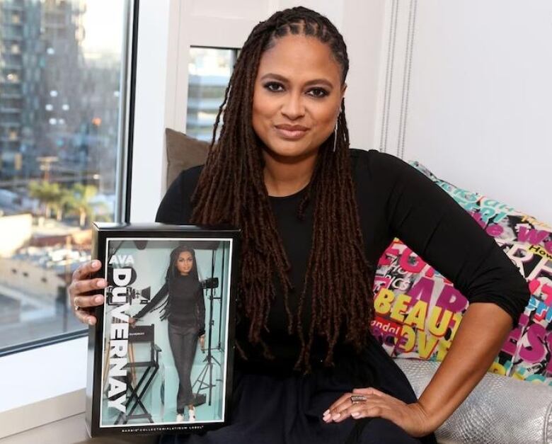 Ava DuVernay poses with a Barbie-sized doll of her likeness