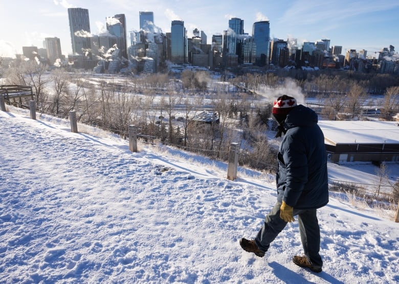 A man walks past the skyline of a city in winter.