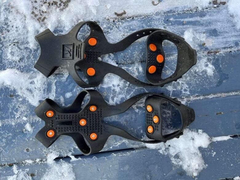 Pair of ice grippers for shoes lying on snowy/icy ground.