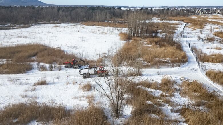 Aerial view of a snowy winter landscape with a few fences and two heavy vehicles.