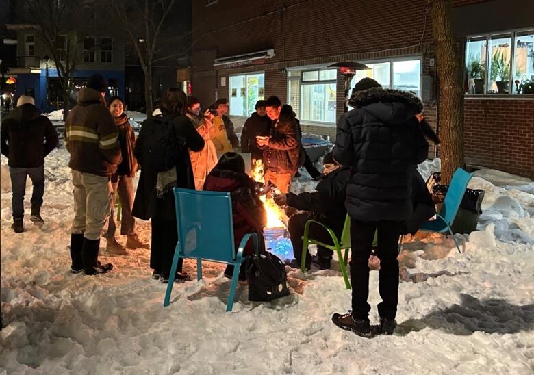 A group of people stand around a fire.