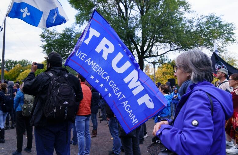 A man carries a blue Donald Trump flag at a rally.